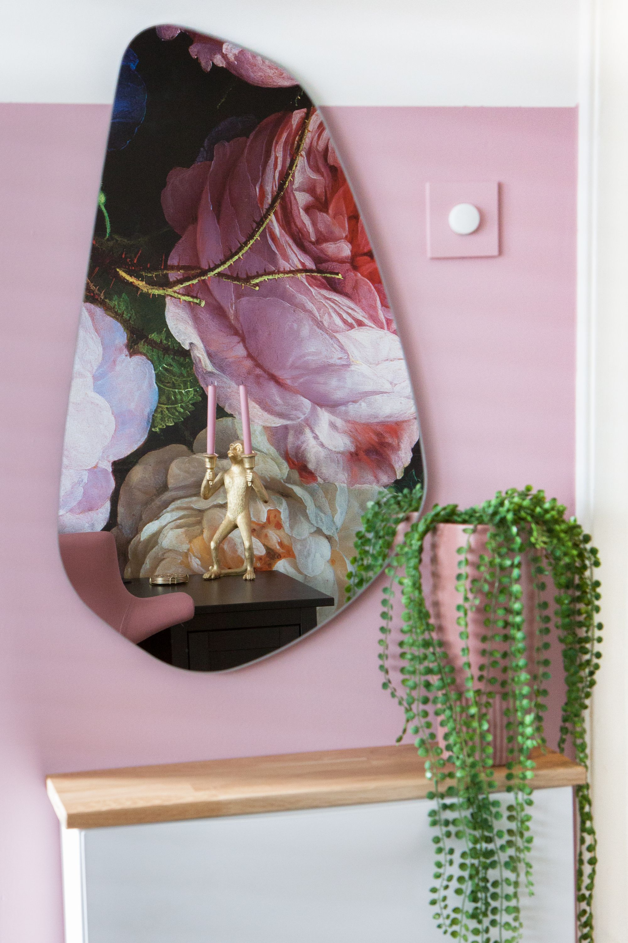 Organische spiegel met bloempot op roze muur met lambrisering