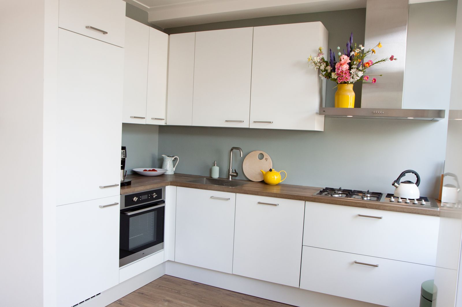 Witte basic keuken met RVS greepjes en een houten blad.