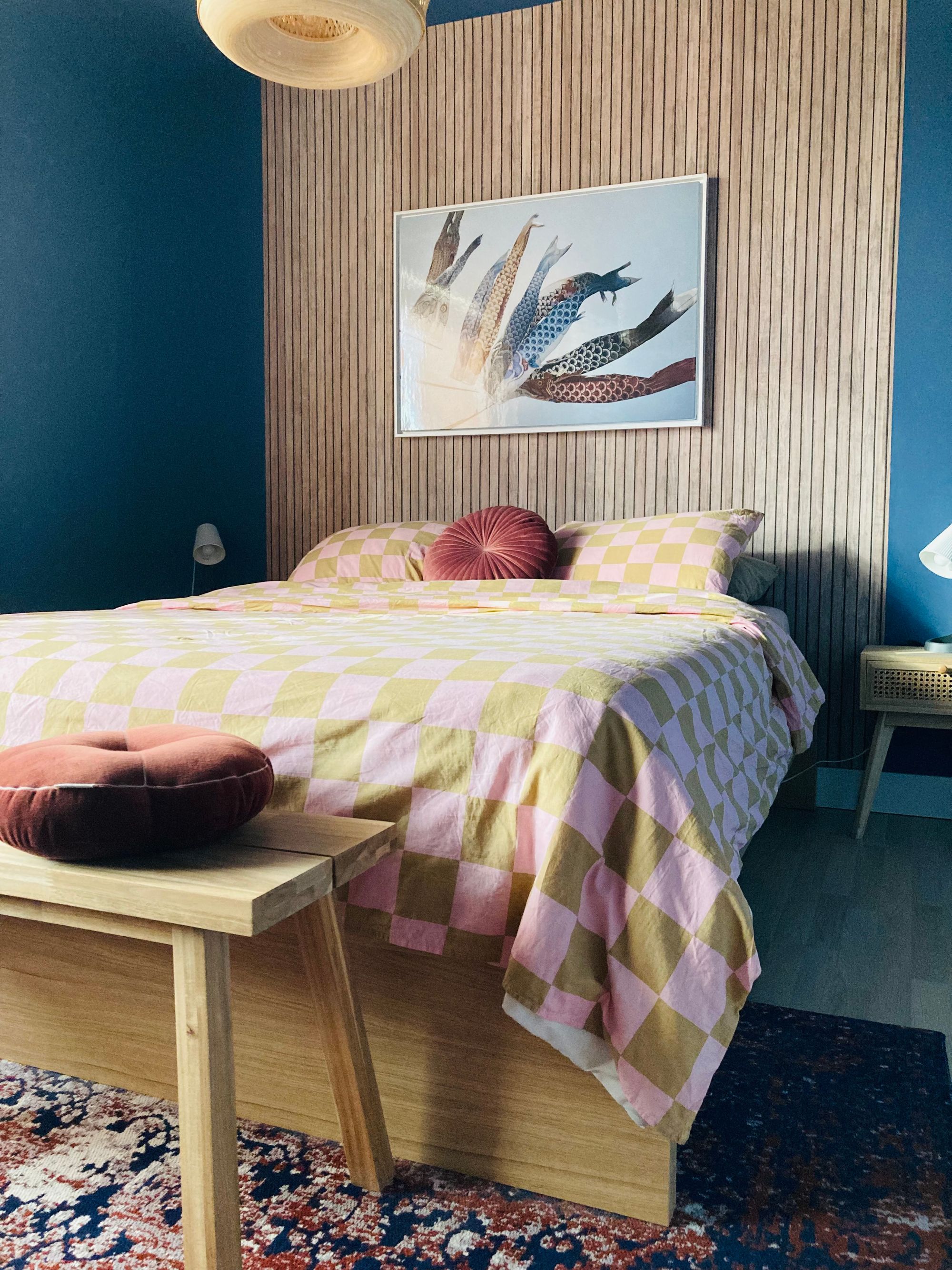 Slaapkamer met houten latjes wand en een geblokt dekbedovertrek
