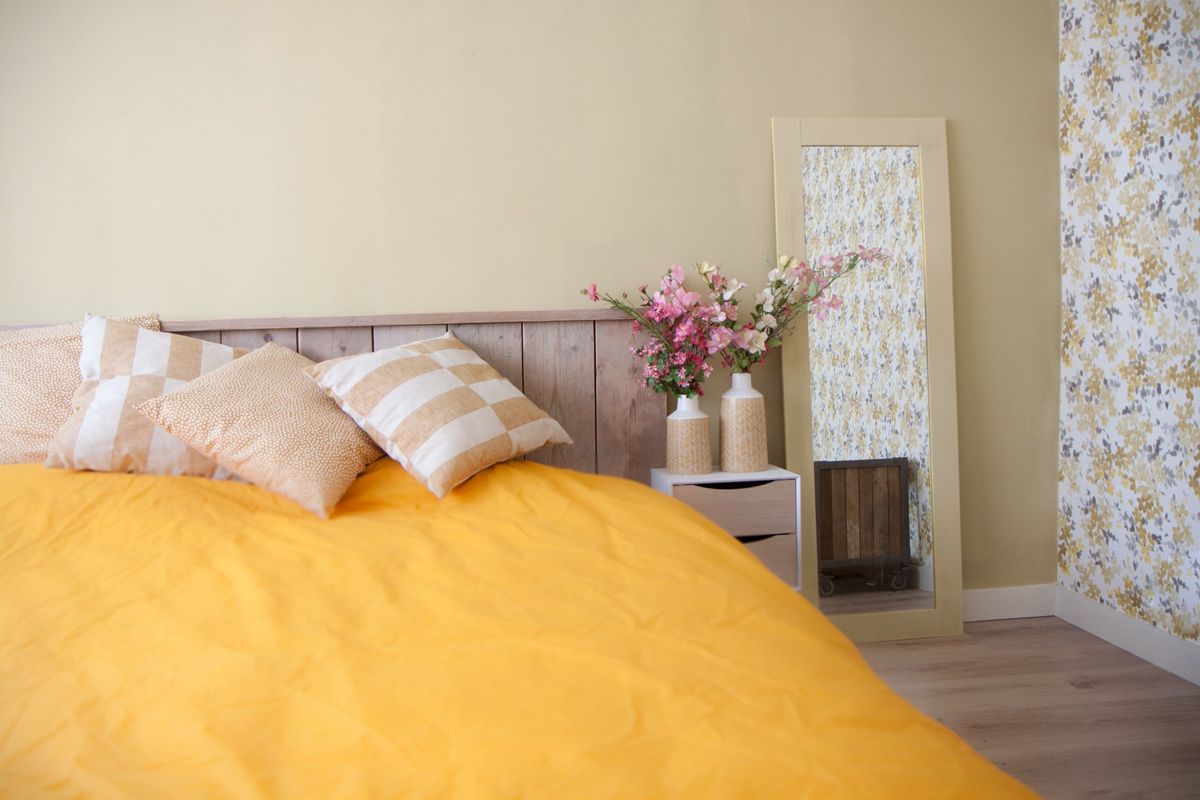Slaapkamer met geel dekbedovertrek en bloemetjesbehang