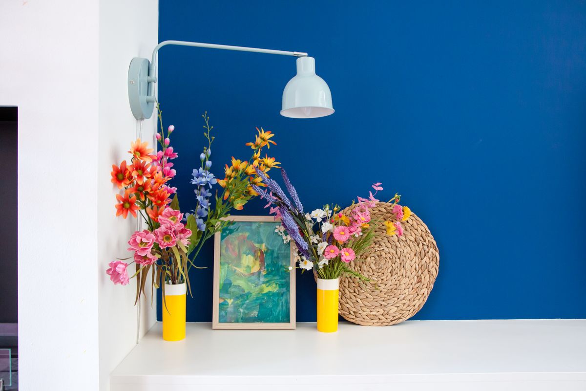Donkerblauwe muur in de woonkamer met kleurrijke accessoires